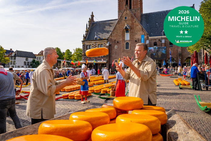 Kaasmeisjes houden een grote ronde kaas vast op de kaasmarkt in Alkmaar